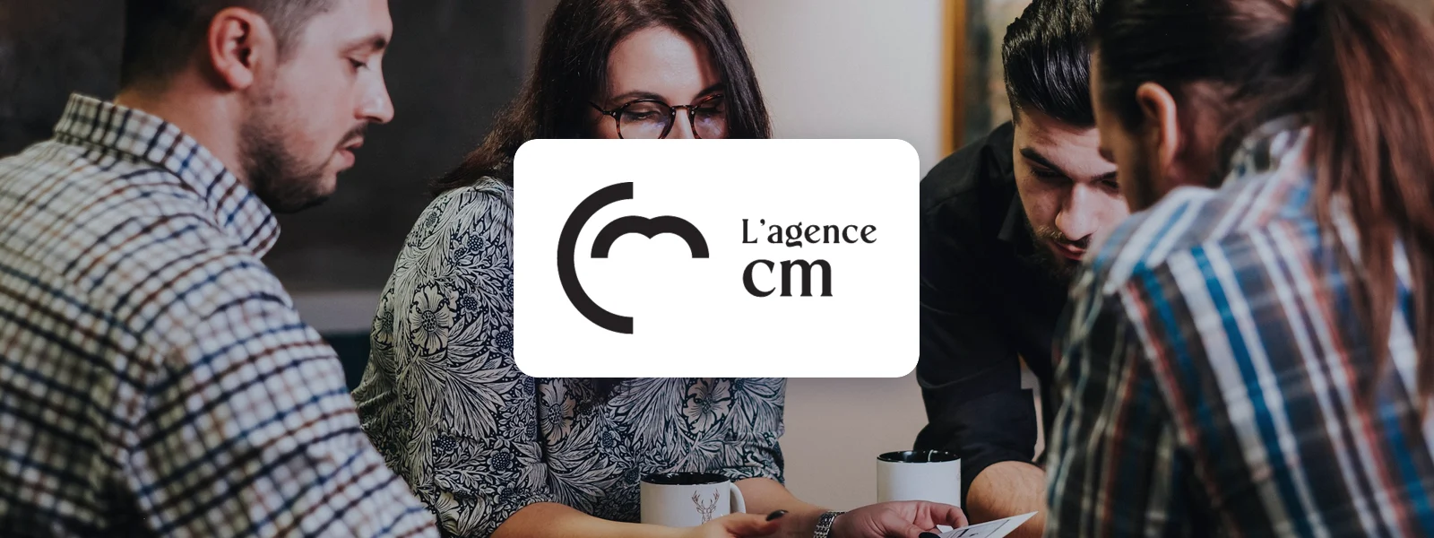 Logo de L’Agence CM sur une photo d’équipe au travail autour d’une table