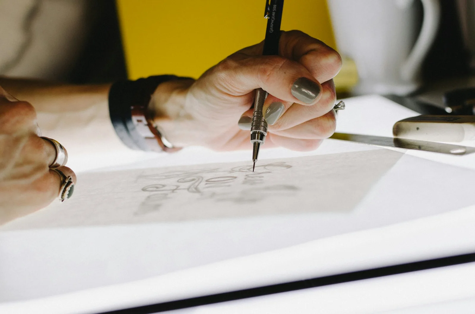 Main traçant des lettres au crayon sur papier calque