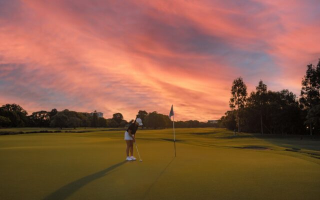 Golfeuse sur un green au coucher du soleil
